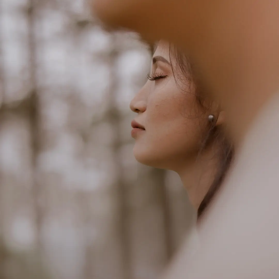 woman in nature eyes closed with trees in background